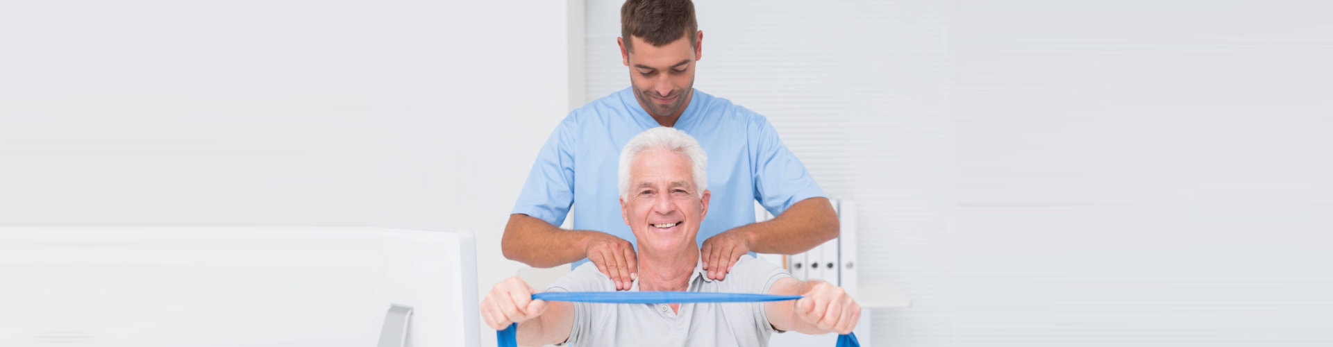 male physiotherapist assisting senior patient in exercising